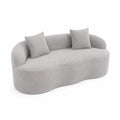 Sofá curvado de tela bouclé gris claro con cojines